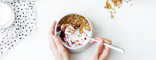 woman trying to improve eating habits by eating a healthy bowl of granola and yoghurt