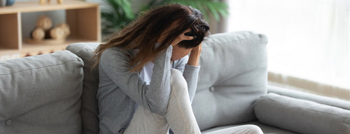 woman with bad headache sitting on the couch with her head in her hands