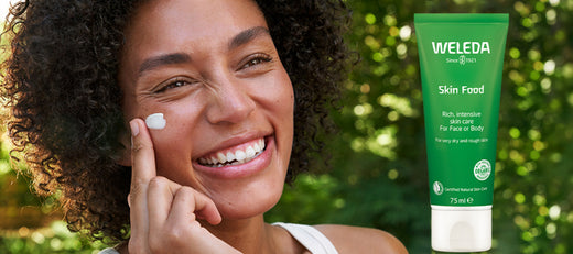 smiling woman applying face cream and green bottle of weleda skin food