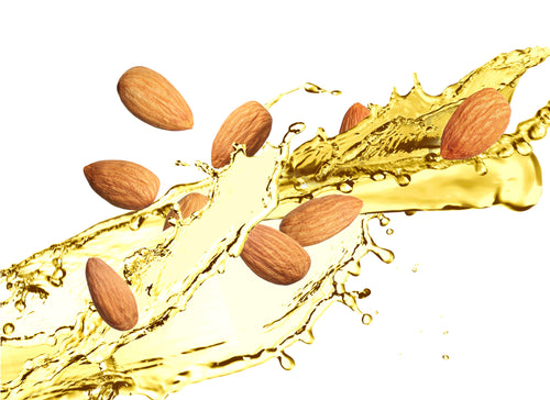 whole almonds with splashes of almond oil on white background