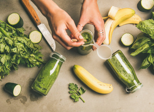 flat lay shot of woman's hands preparing a green smoothie