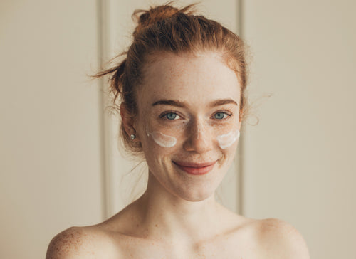 smiling girl with eye cream under eyes