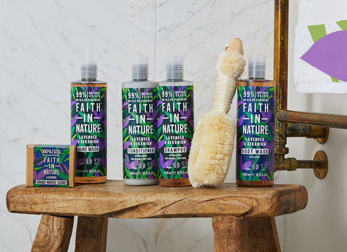 bottles of faith in nature bath and hair products on a wooden stool with a loofah