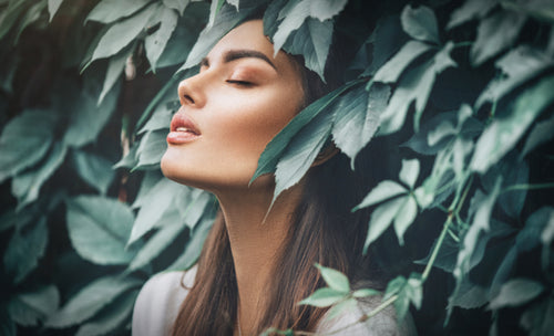 relaxed woman surrounded with green leaves
