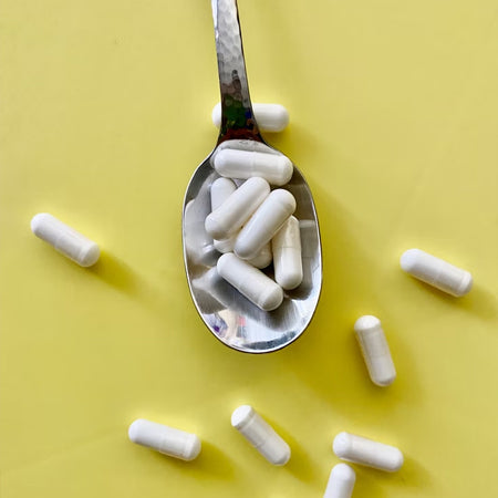 metal spoon with powdered capsules, gluten free supplements