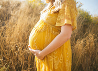 pregnany woman in yellow dress in corn field