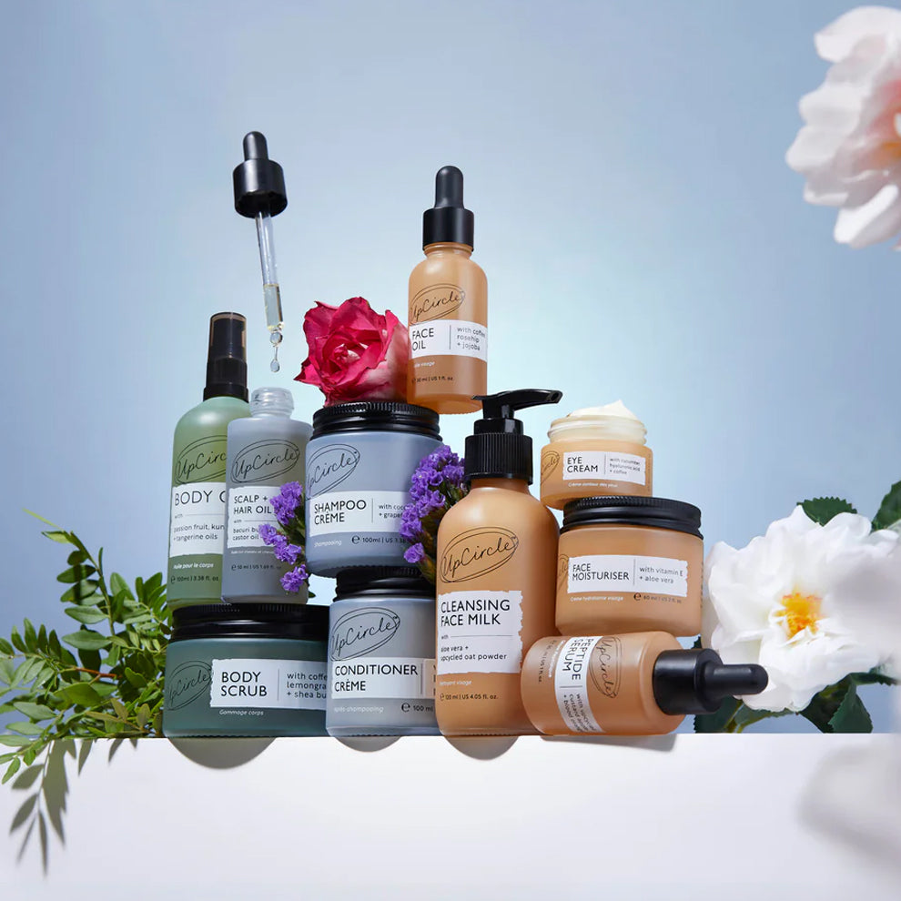 Collection of UpCircle skincare and hair care products with flowers on a light blue background