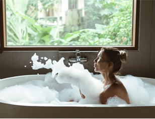 Woman in a bath blowing bath foam