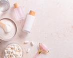 Skincare products and tools on a pale pink background