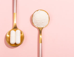 Gold spoons holding white collagen powder and white capsules on pink background