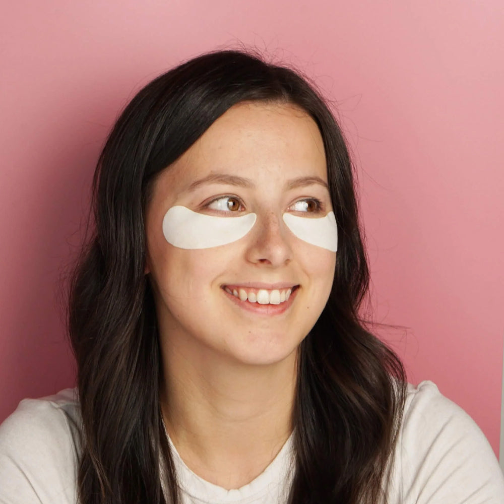 Woman wearing eye masks against a pink background