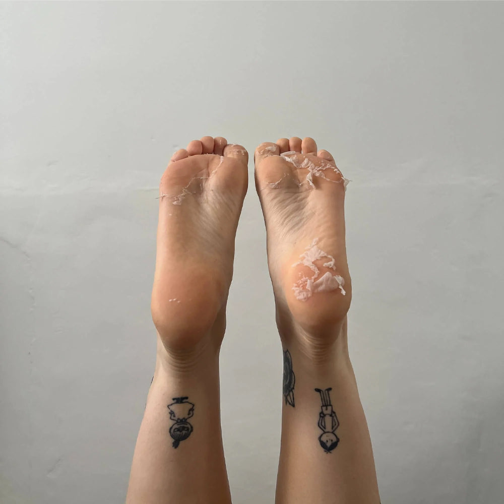 Two feet with clear plastic wrap on toes against a plain background