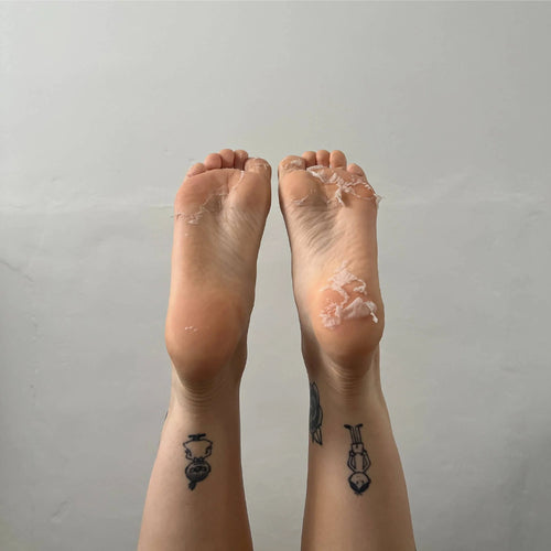 Two feet with clear plastic wrap on toes against a plain background