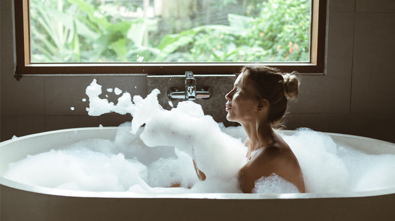 woman in bubble bath blowing bath foam