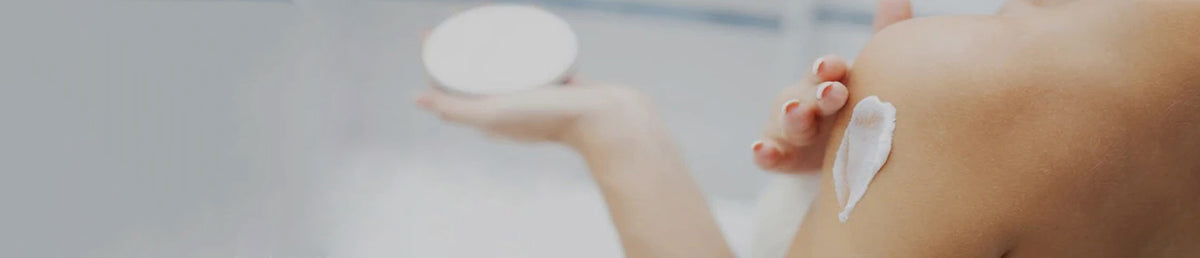 A close-up lifestyle shot of a person applying lotion onto their upper arm