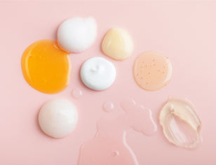 Selection of different textures gels and creams on a pink background