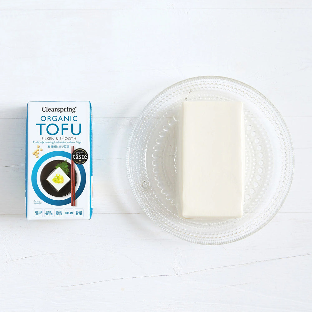 Clearspring Organic Tofu package next to a block of tofu on a white plate