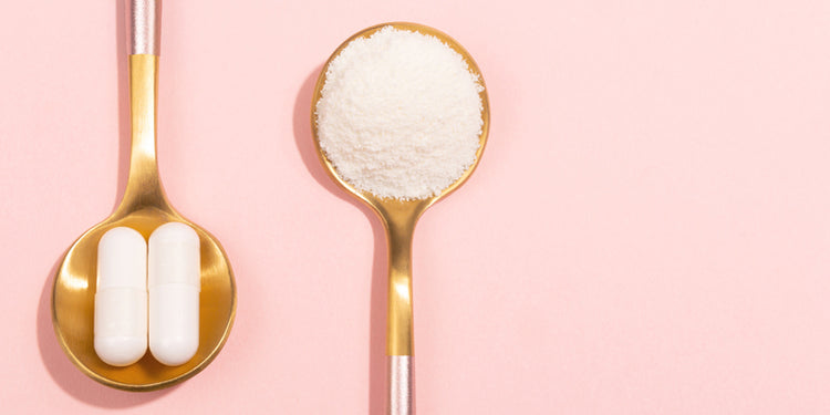 Gold spoons holding white capsules and white powder on a pink background
