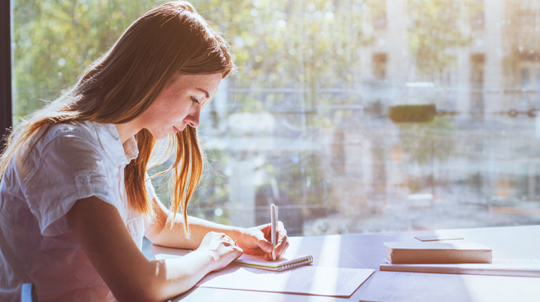 girl writing in a notebook at a desk