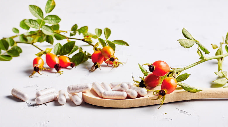 cranberry capsules on a wooden spoon with plant