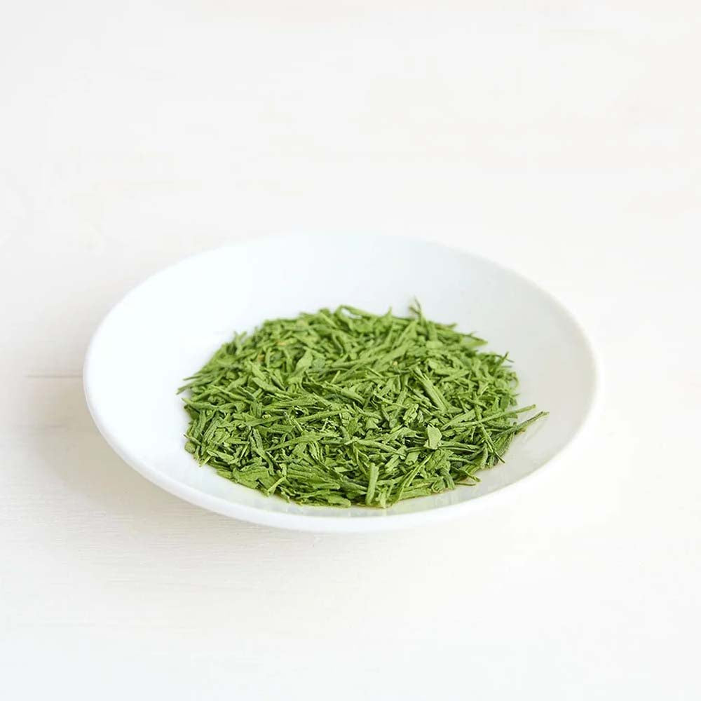 Clearspring Matcha Sencha green tea leaves on a white plate with a white background