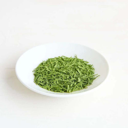 Clearspring Matcha Sencha green tea leaves on a white plate with a white background