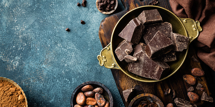 Chocolate, cacao beans and cacao powder in bowls on grey background