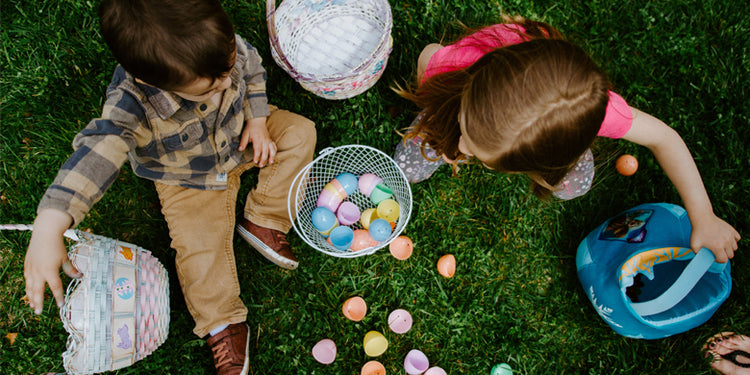 Children sitting on grass surrounded by eggs from Easter hunt