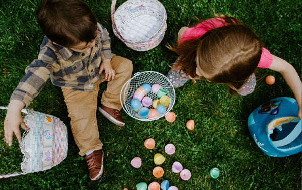 Children sitting on grass sharing out Easter eggs