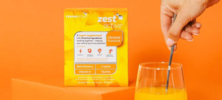Zest Active supplement package with a glass of orange juice on an orange background