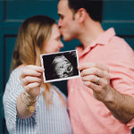 woman and man holding a scan of an unborn baby