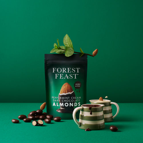 Packaging of Forest Feast Peppermint Cream Dark Chocolate Almonds with two mugs on a green background