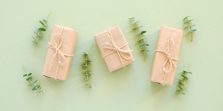 Gifts wrapped in brown kraft paper on a pale green background
