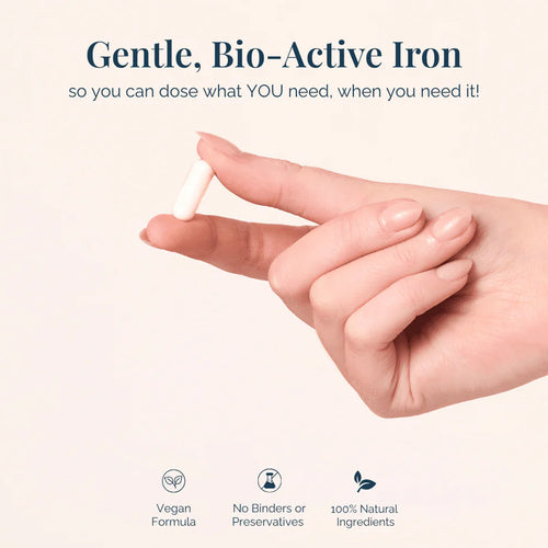 Hand holding a small iron supplement with promotional text about gentle, bio-active iron on a light background.