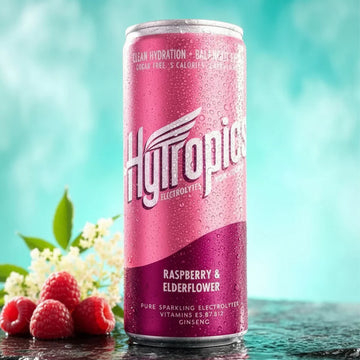 Pink can of Hytropic Raspberry &amp; Elderflower drink with raspberries and flowers on a teal background