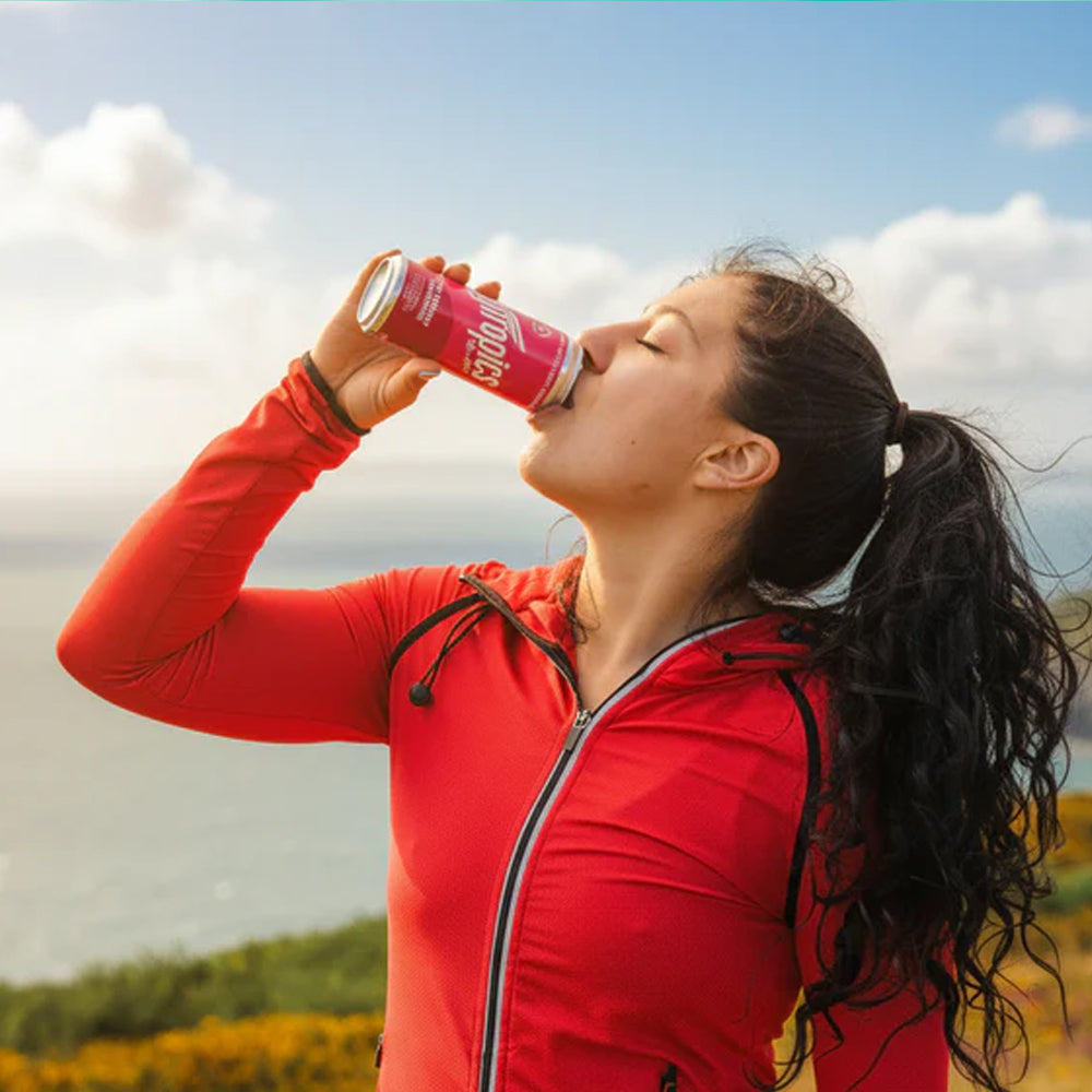 Person in red jacket drinking from a can outdoors