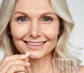 Smiling woman about to take tablet with water