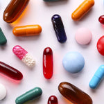 coloured tablets and capsules on a pink background