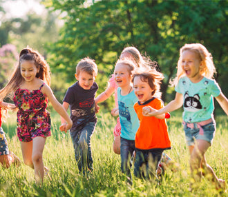 Smiling children holding hands running through grass