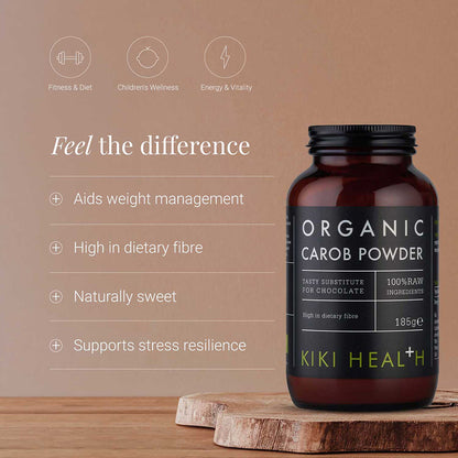 A bottle of Kiki Health Organic Carob Powder sits on a wooden surface against a warm brown background with marketing text and icons about fitness and wellness.