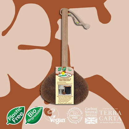 A LooCo hand-washed brown coconut coir brush with a light wood handle and a white drawstring, shown with its product tag against a beige and brown abstract background. Certification badges for &