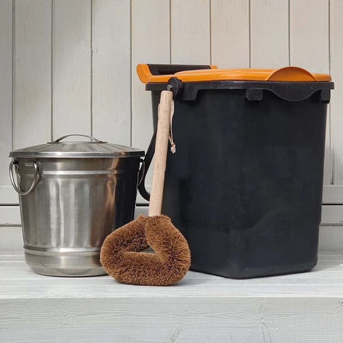 Cleaning supplies including a metal bucket, black trash bin, and brown scrubber on a wooden floor.