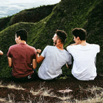 laughing men sitting together on hillside