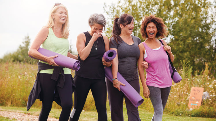 smiling women walking together with yoga mats