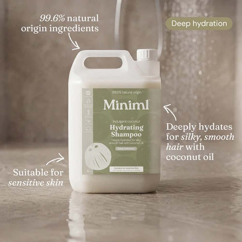 A large white plastic bottle of Minim1 Hydrating Shampoo with a sage green label, shown on a glossy tiled floor with marketing text callouts around it.
