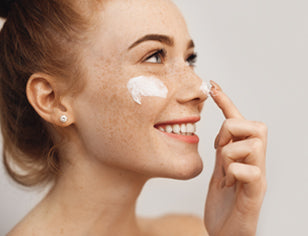 smiling girl applying moisturiser to her face