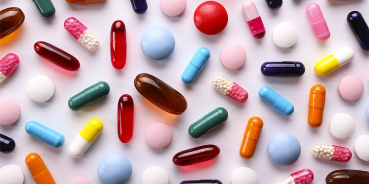 Colourful tablets and capsules on a pink background