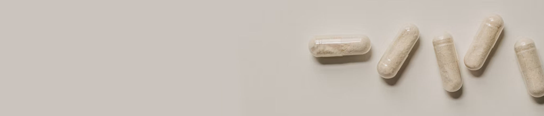 Four off-white L-Theanine capsules arranged diagonally on a plain light gray background.