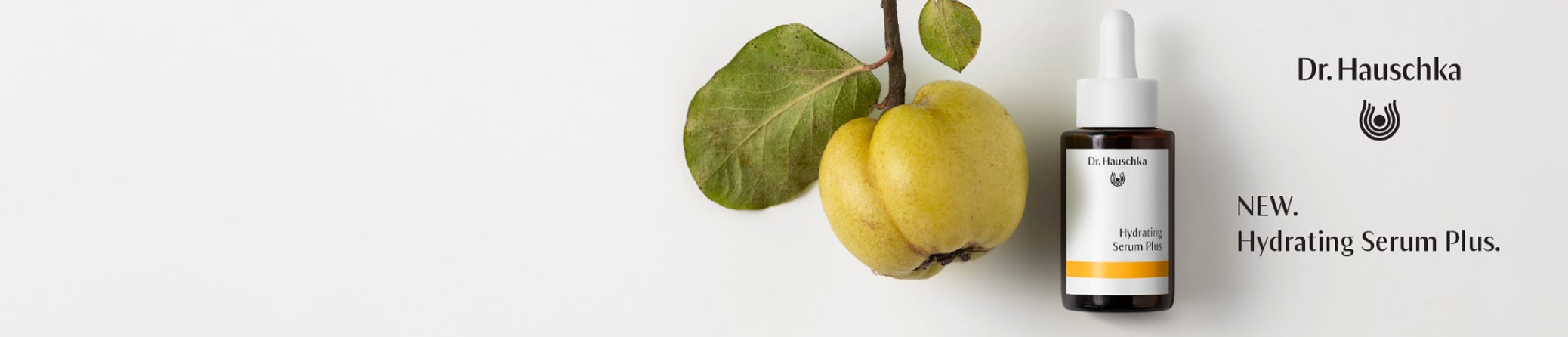 A small white dropper bottle labeled Dr. Hauschka Hydrating Serum Plus stands on a white background beside a green leafy fruit.