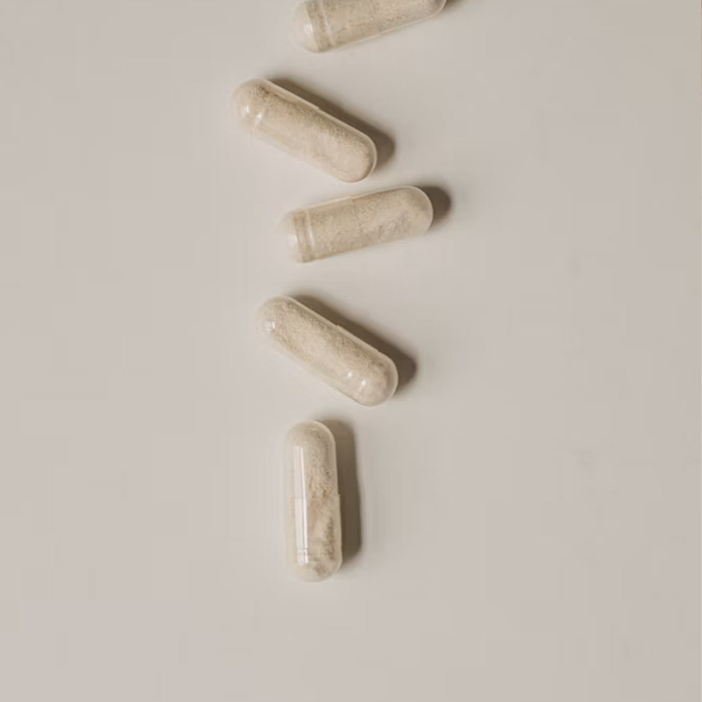 Four off-white L-Theanine capsules arranged diagonally on a plain light gray background.